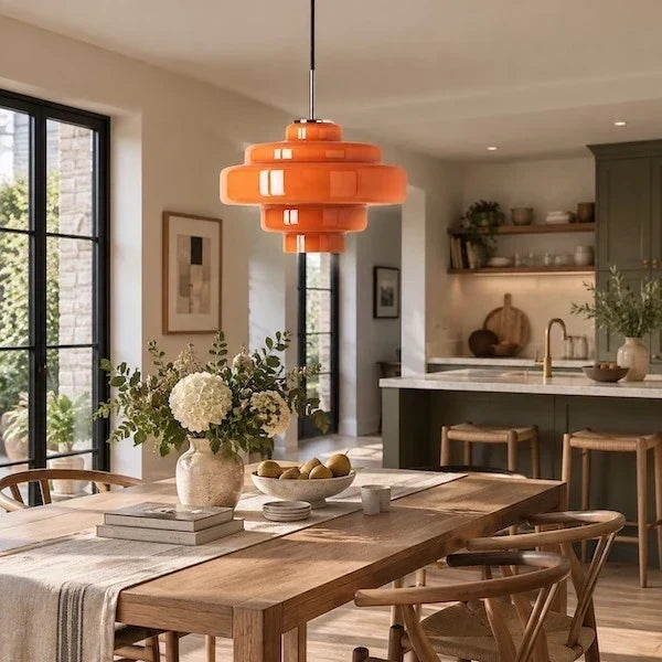 Glass pendant lighting positioned between a dining table and kitchen island in a lived-in home