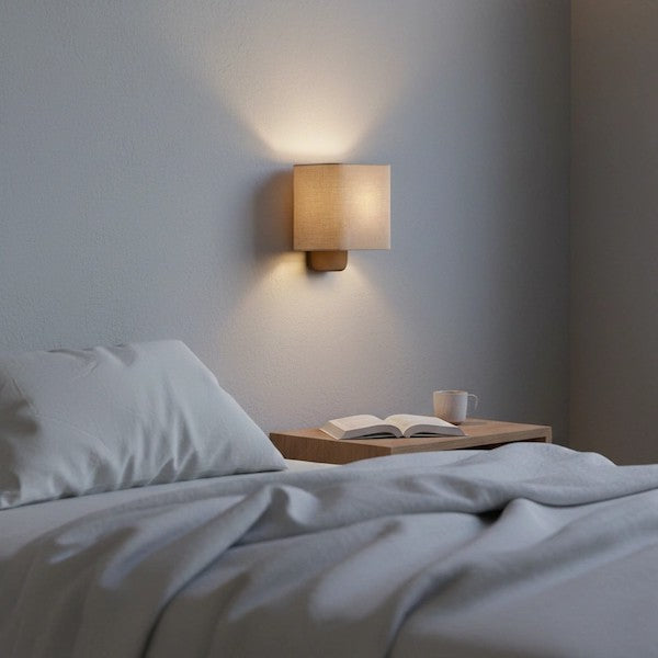 A Nordic style bedroom featuring a warm glowing linen wall sconce above a bedside table.