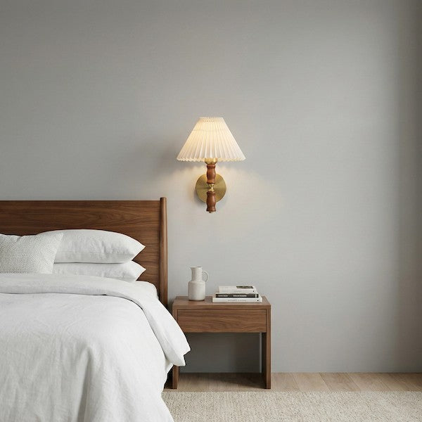 A side-view diagram of a bedroom showing a walnut wall light mounted at shoulder height next to a person sitting in bed.