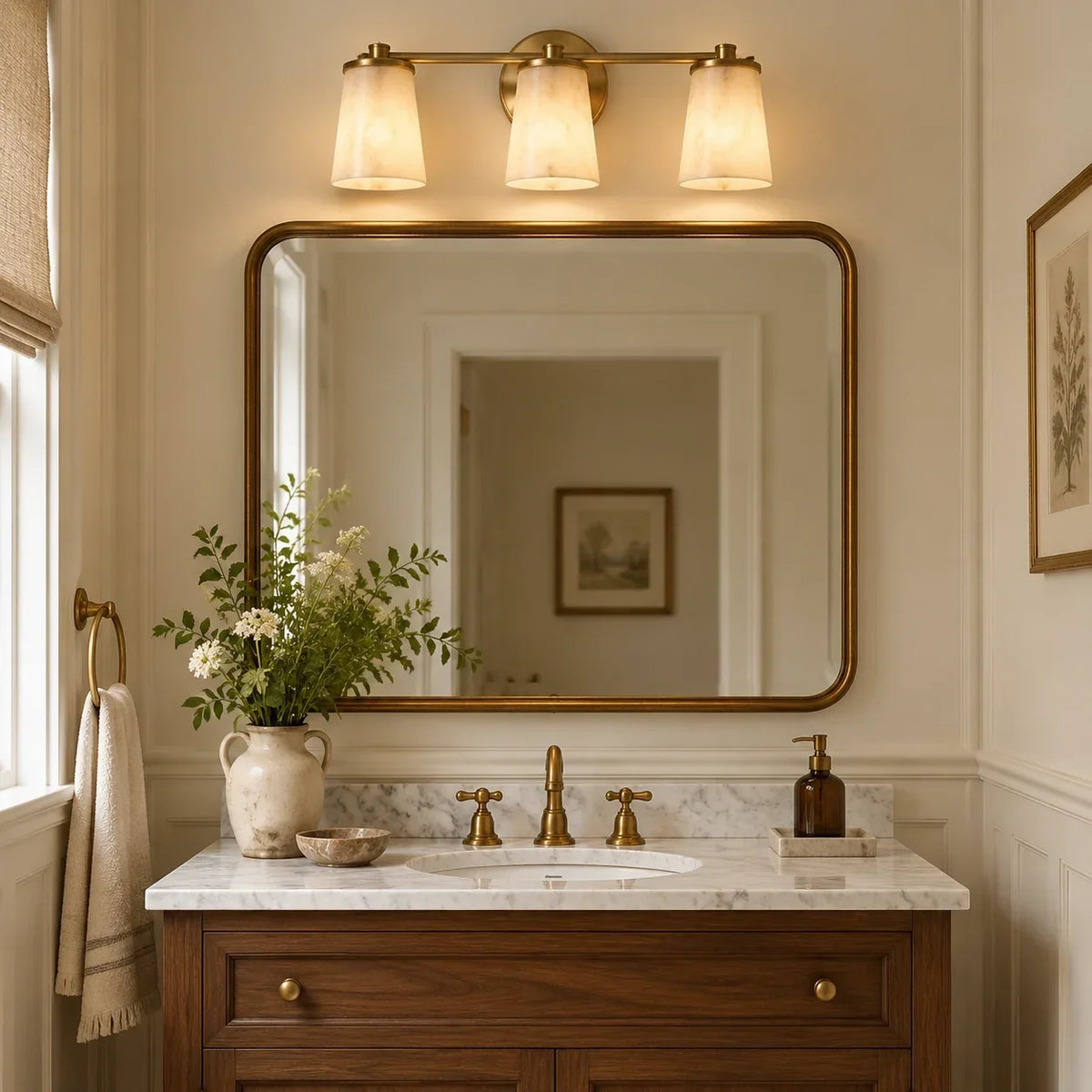 Three-light alabaster and brass wall light above a vanity mirror